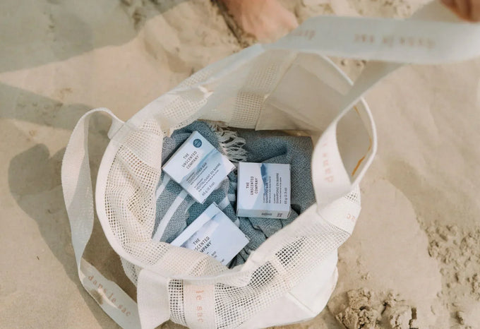 Travel tote bag with fragrance free shampoo and conditioner bar boxes on a beach