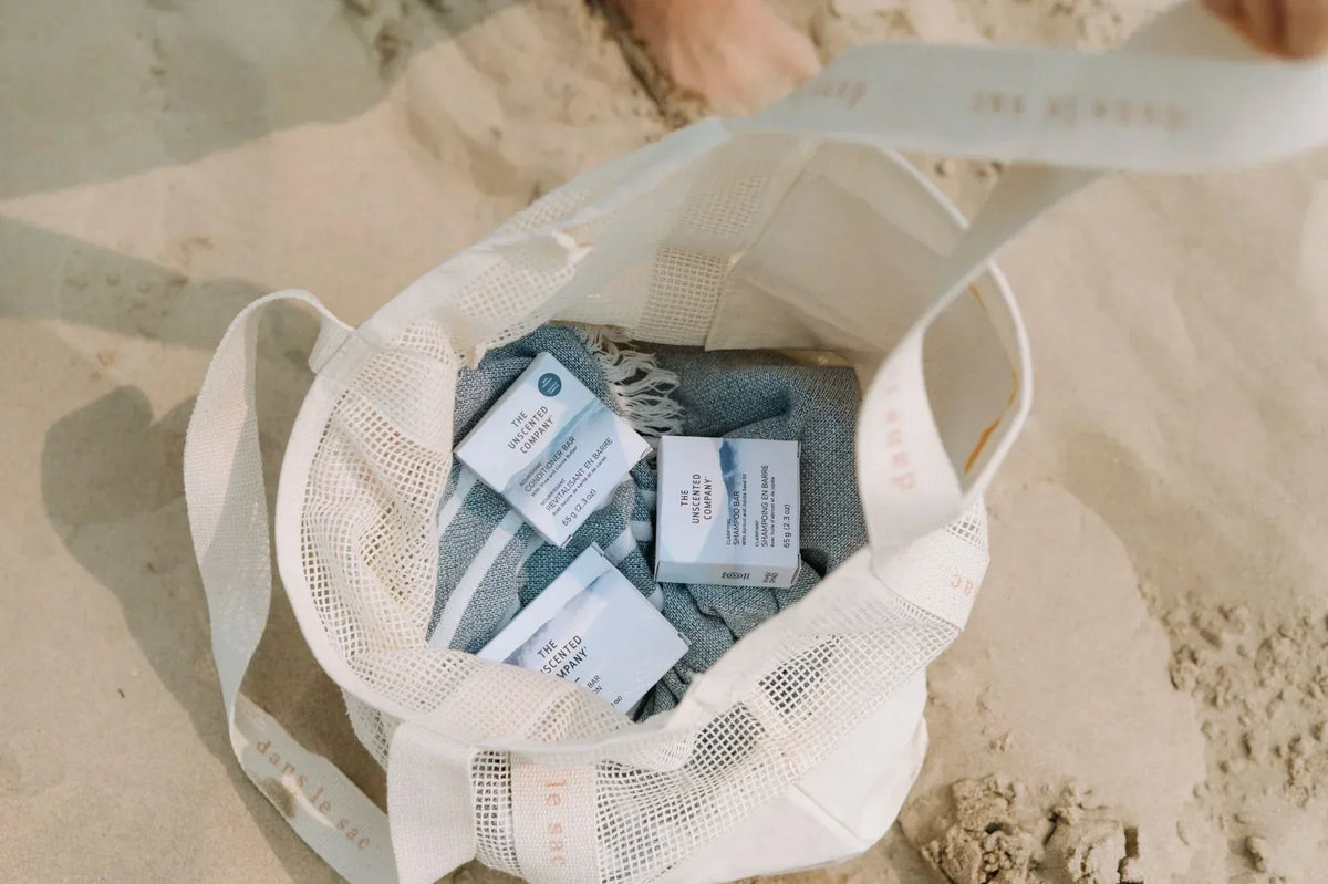 Travel tote bag with fragrance free shampoo and conditioner bar boxes on a beach
