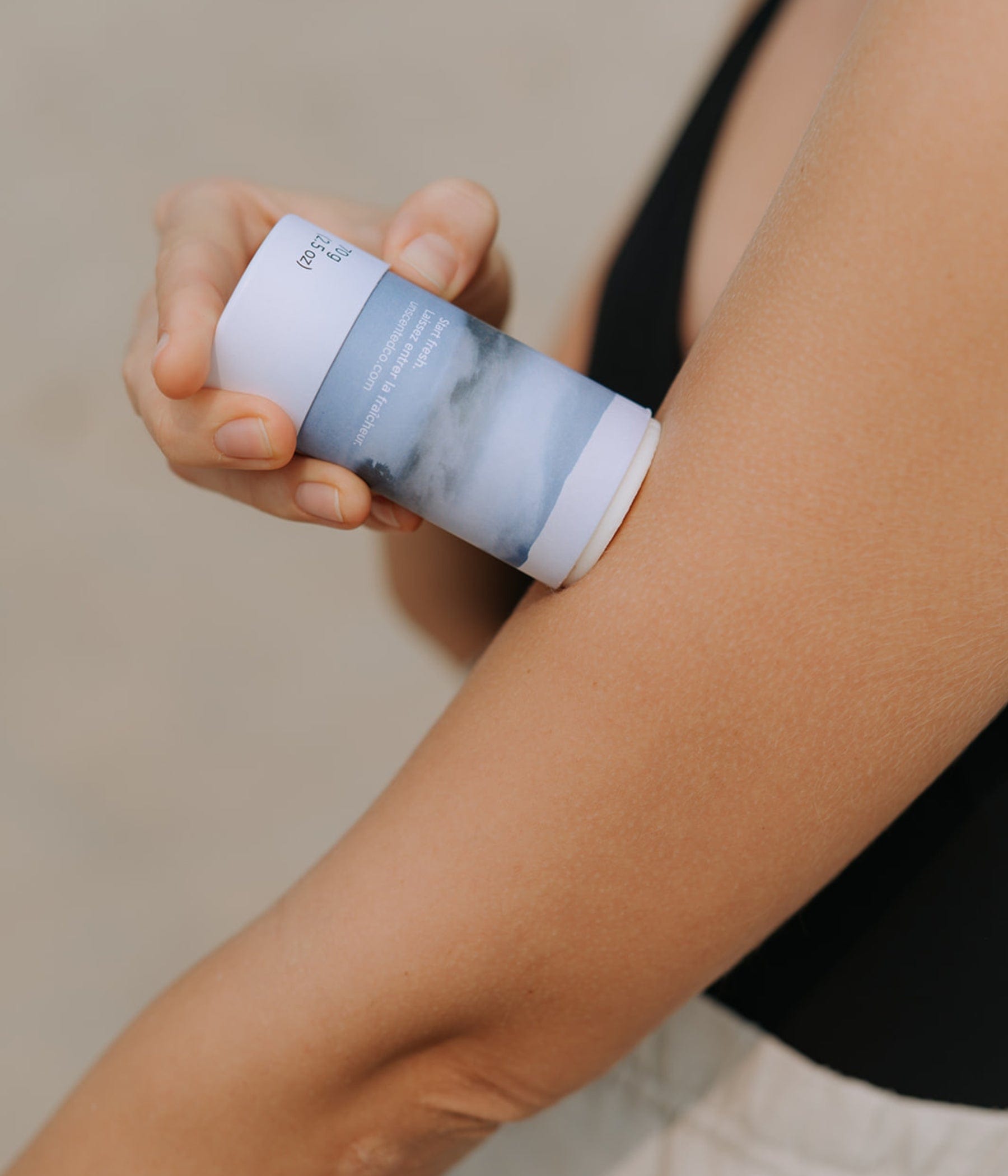 Person applying The Unscented Company’s lotion bar directly to their arm on a beach.