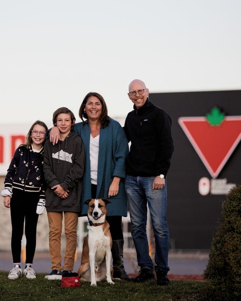 Family and dog smiling in front of a Canadian Tire store.