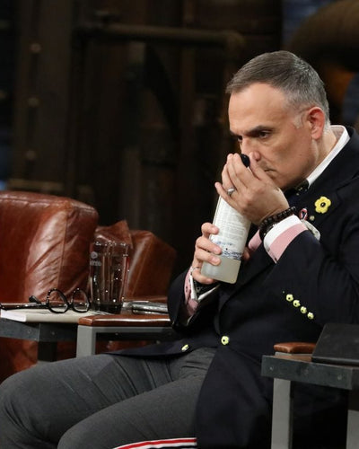 Man smelling a bottle while sitting in a leather chair