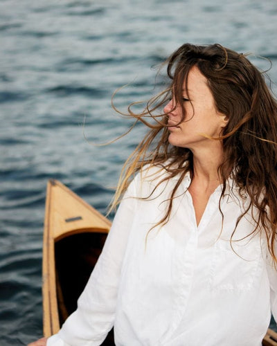 Woman in a white shirt on a boat with wind in her hair.