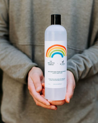 Person holding a bottle of hand sanitizer with a rainbow label.