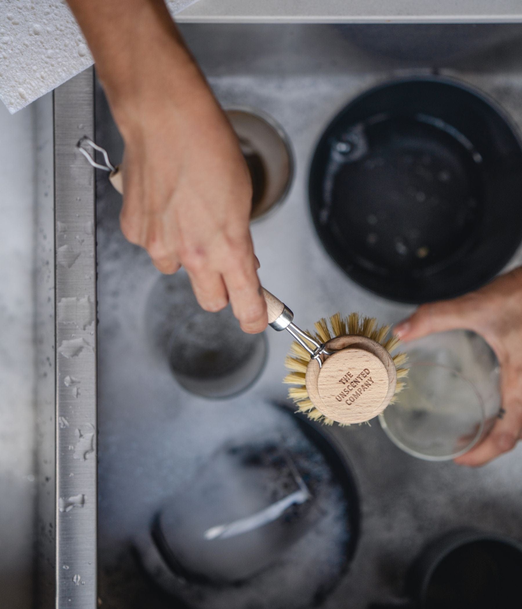Person washing dishes with The Unscented Company dish brush.