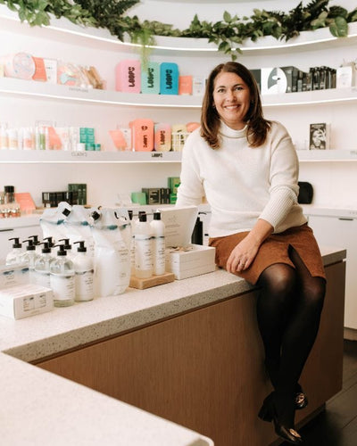 Woman sitting on a counter next to skincare and cleaning products