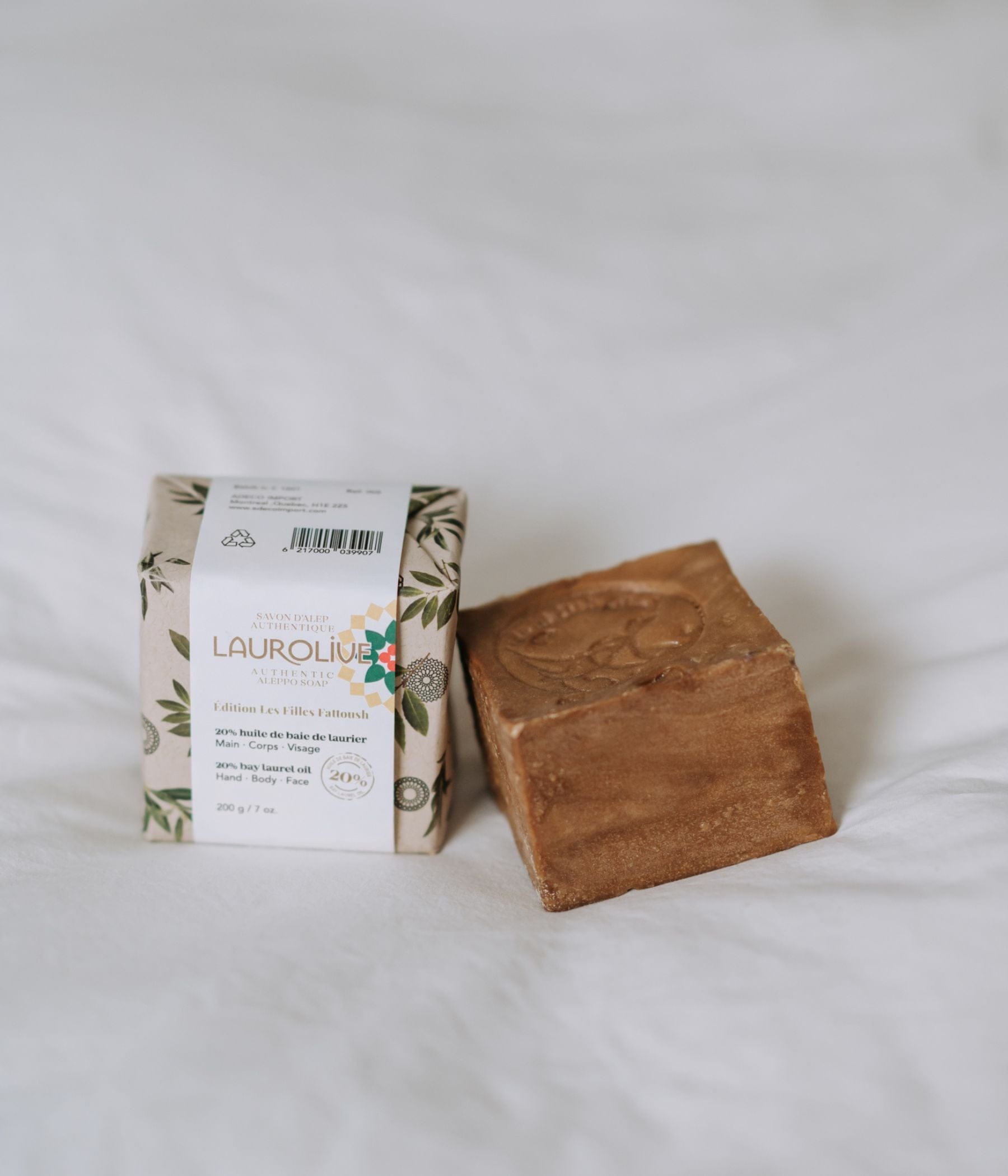 A wrapped and an unwrapped bar of Laurolive soap on a white surface.