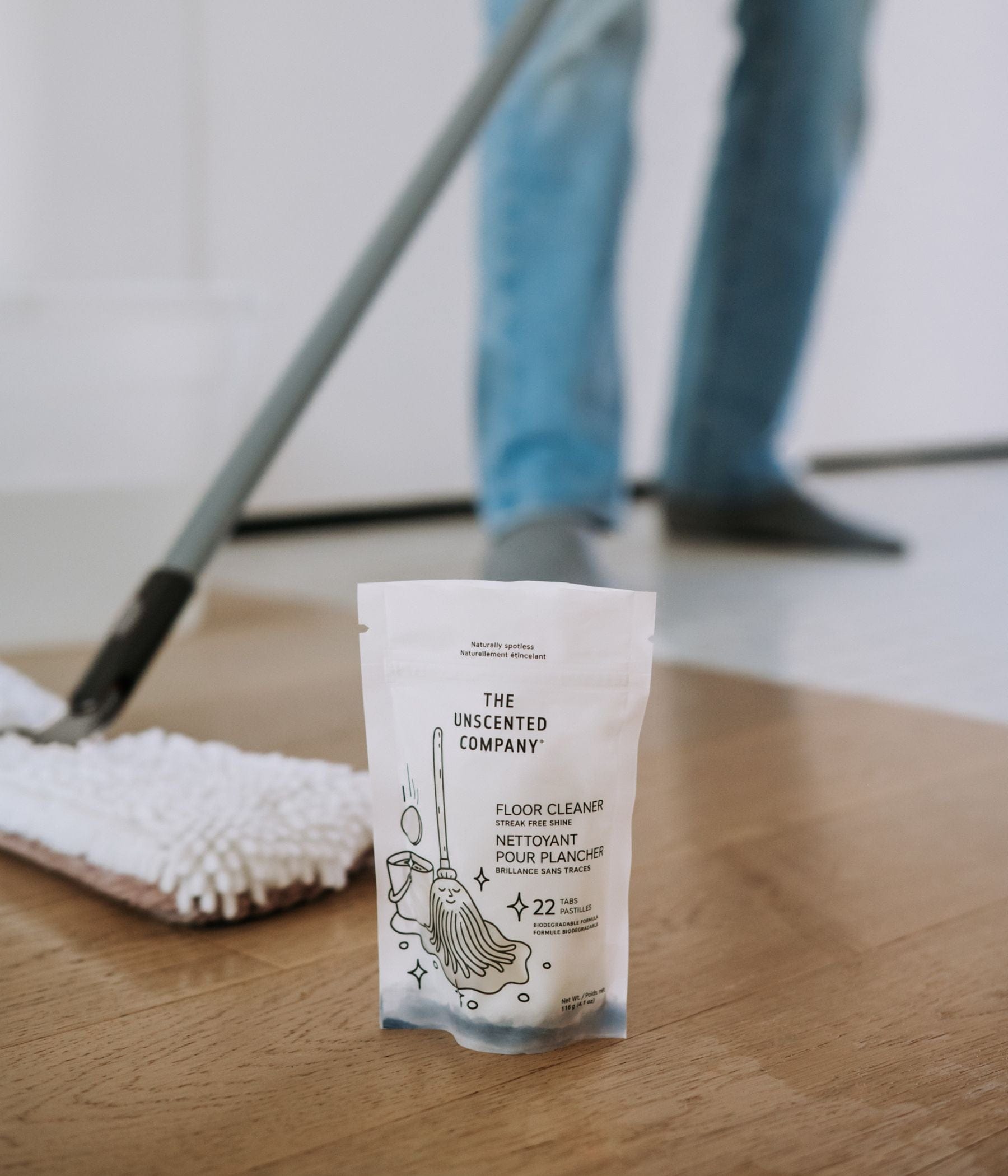 The Floor Cleaner - 22 tabs placed on a the floor with someone using a mop in the background.