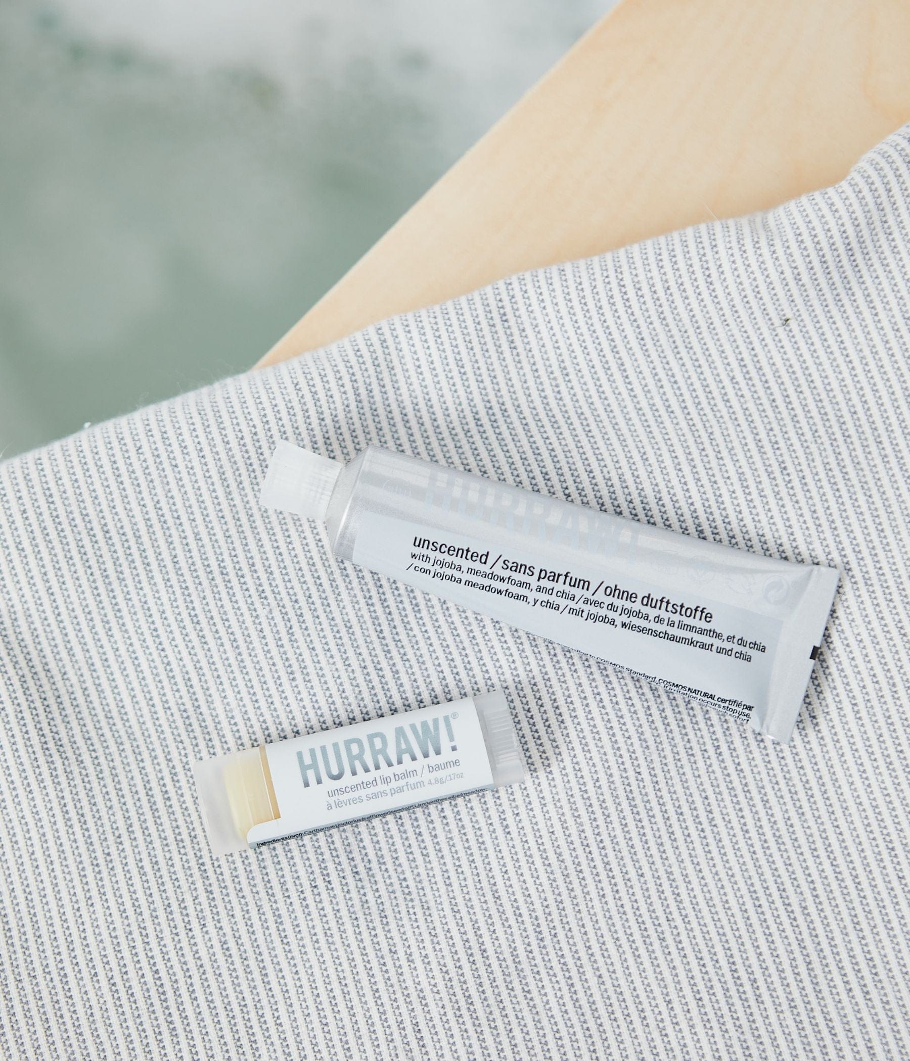 Hurraw! unscented lip balm and tube on a striped towel.