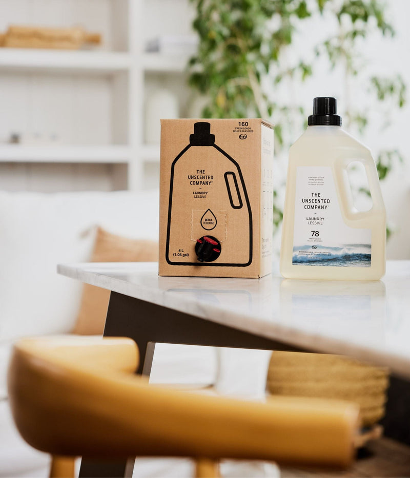 : Laundry detergent bottle and refill box on a table in a cozy room.