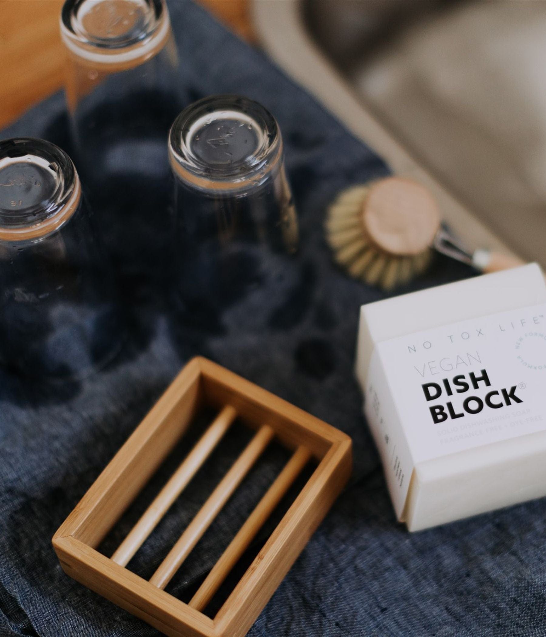 Drying glasses beside a vegan dish soap block and wooden soap tray.