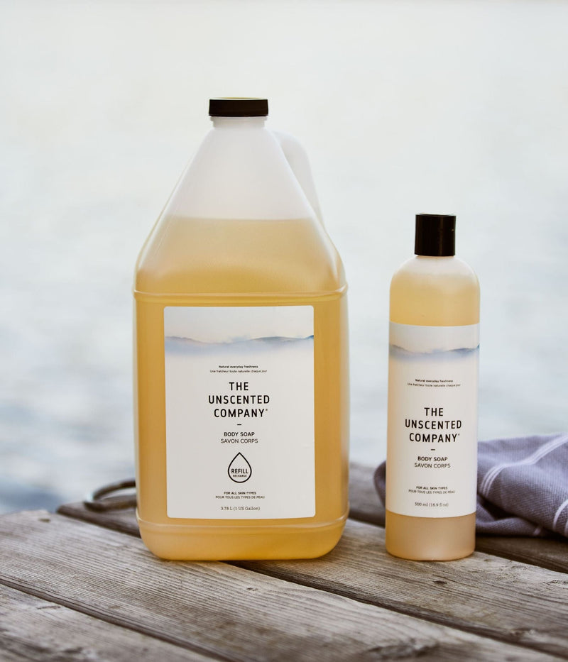 Large refill and regular bottle of body soap from The Unscented Company on a dock.