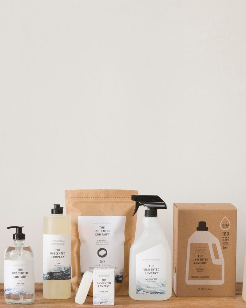 Various cleaning and personal care products from The Unscented Company displayed on a wooden surface.