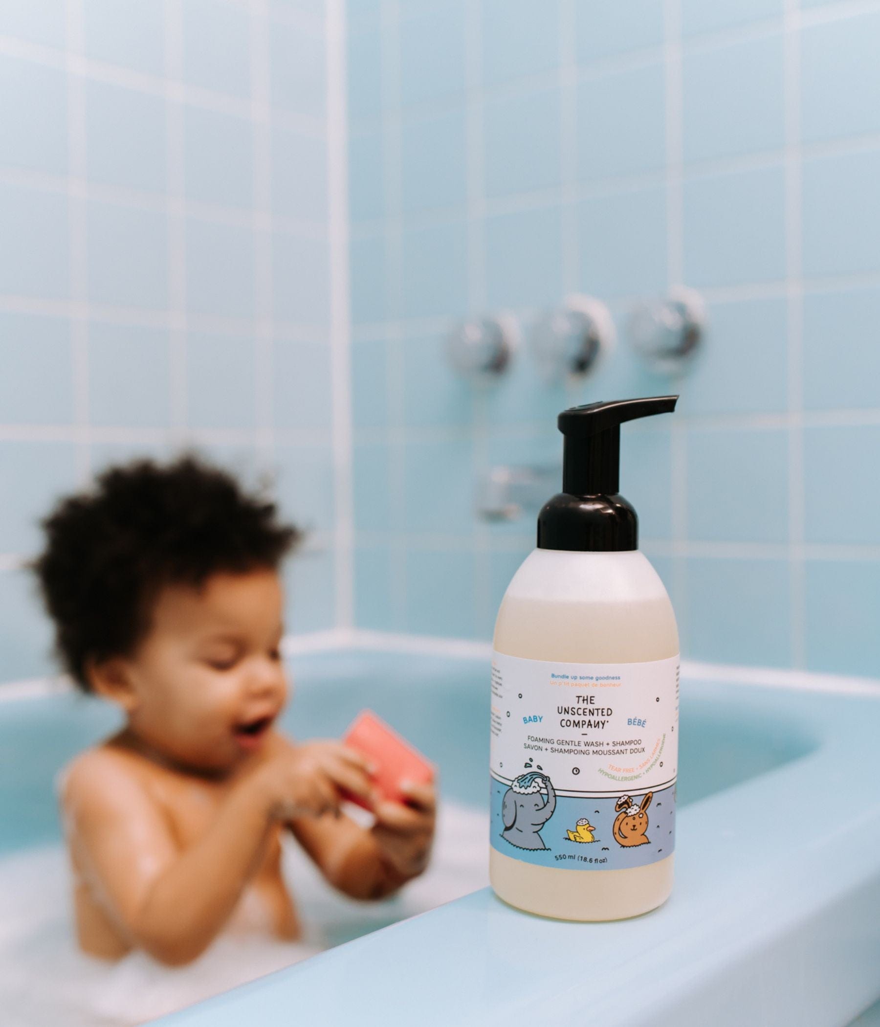 : Baby playing in bathtub with foaming wash bottle.