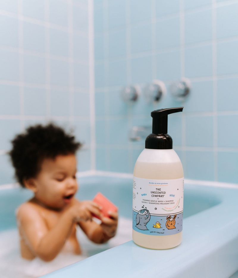 : Baby playing in bathtub with foaming wash bottle.