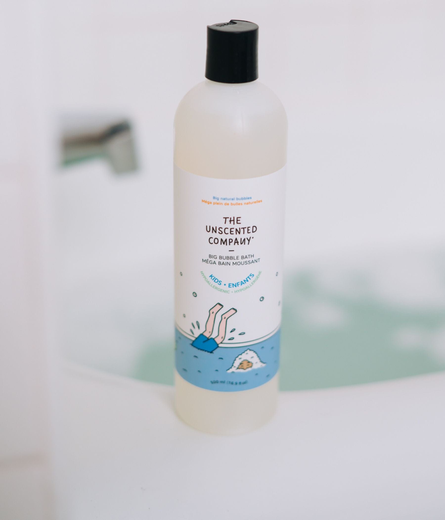 A kids’ bubble bath bottle on the edge of a bathtub.