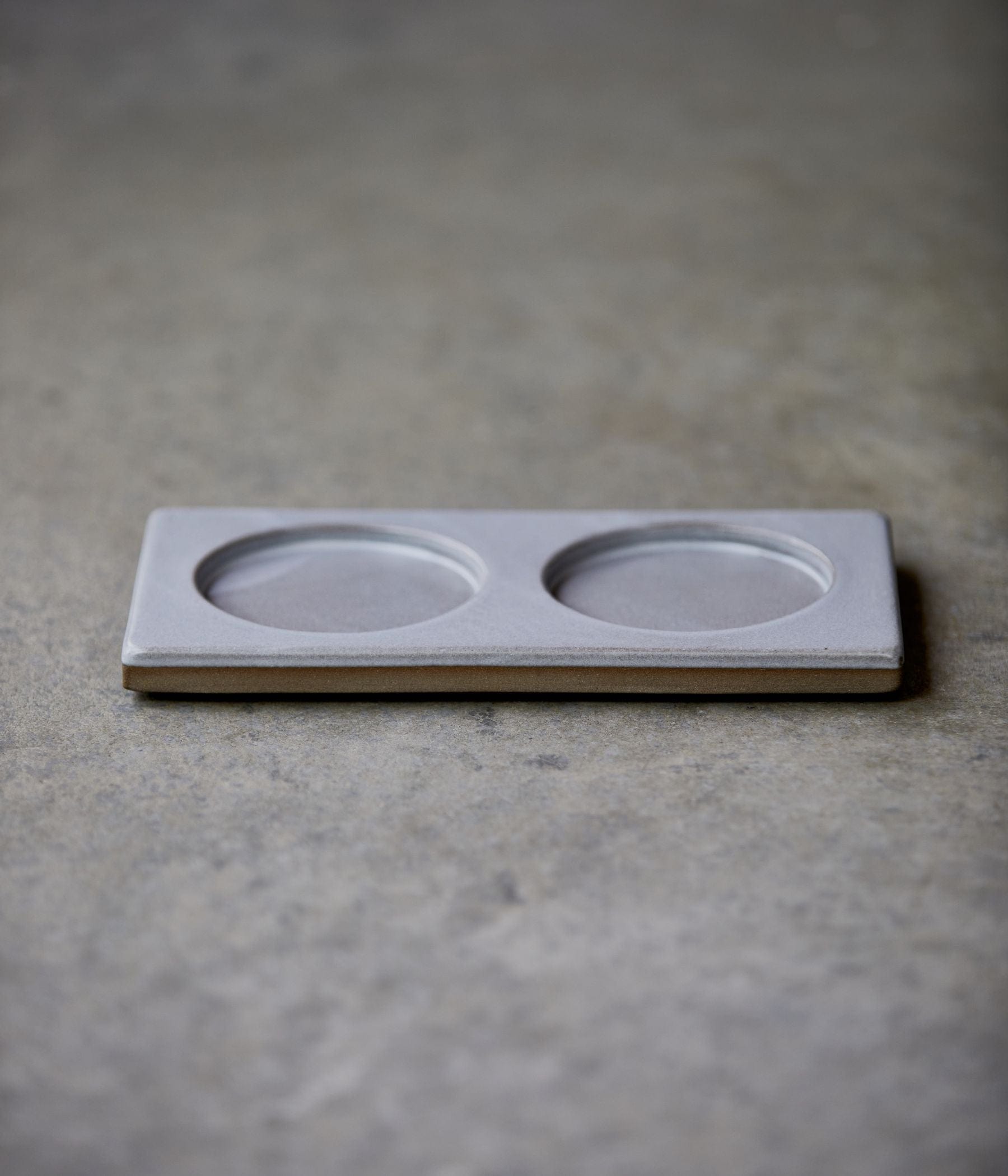 Double circular soap tray on a stone surface.