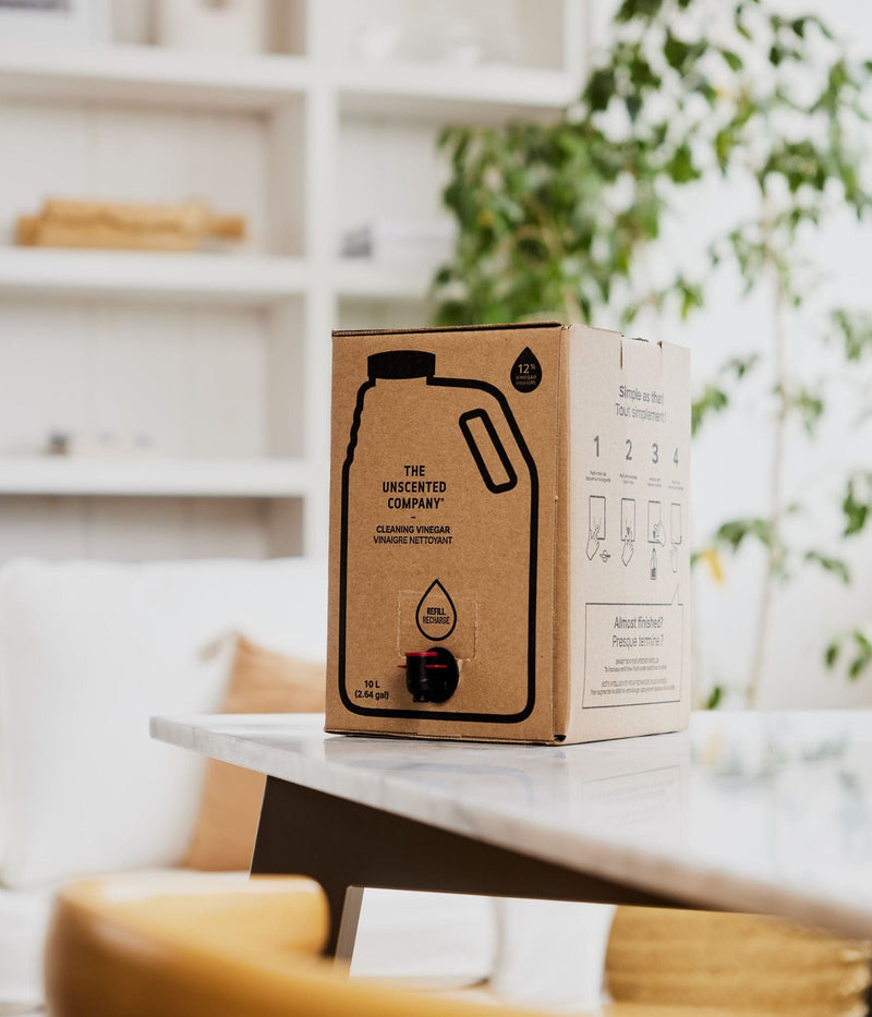 Cardboard box of The Unscented Company cleaning vinegar on a table in a bright room.