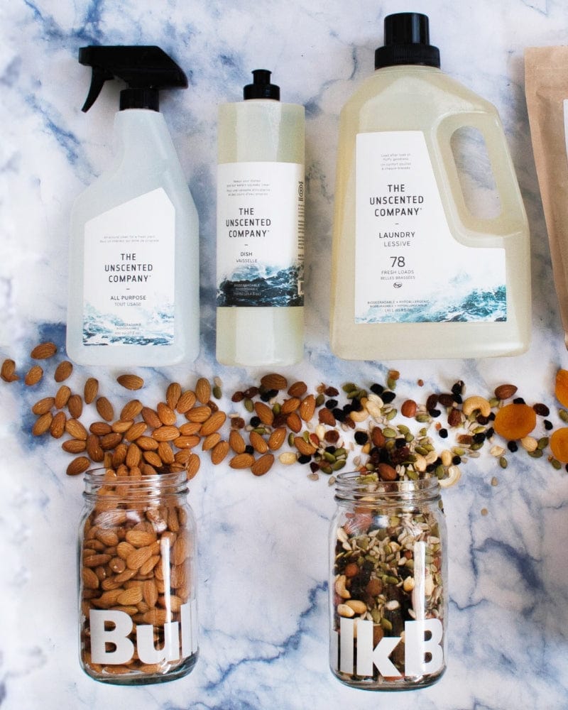 Cleaning products and bulk food items in jars on a marble surface.