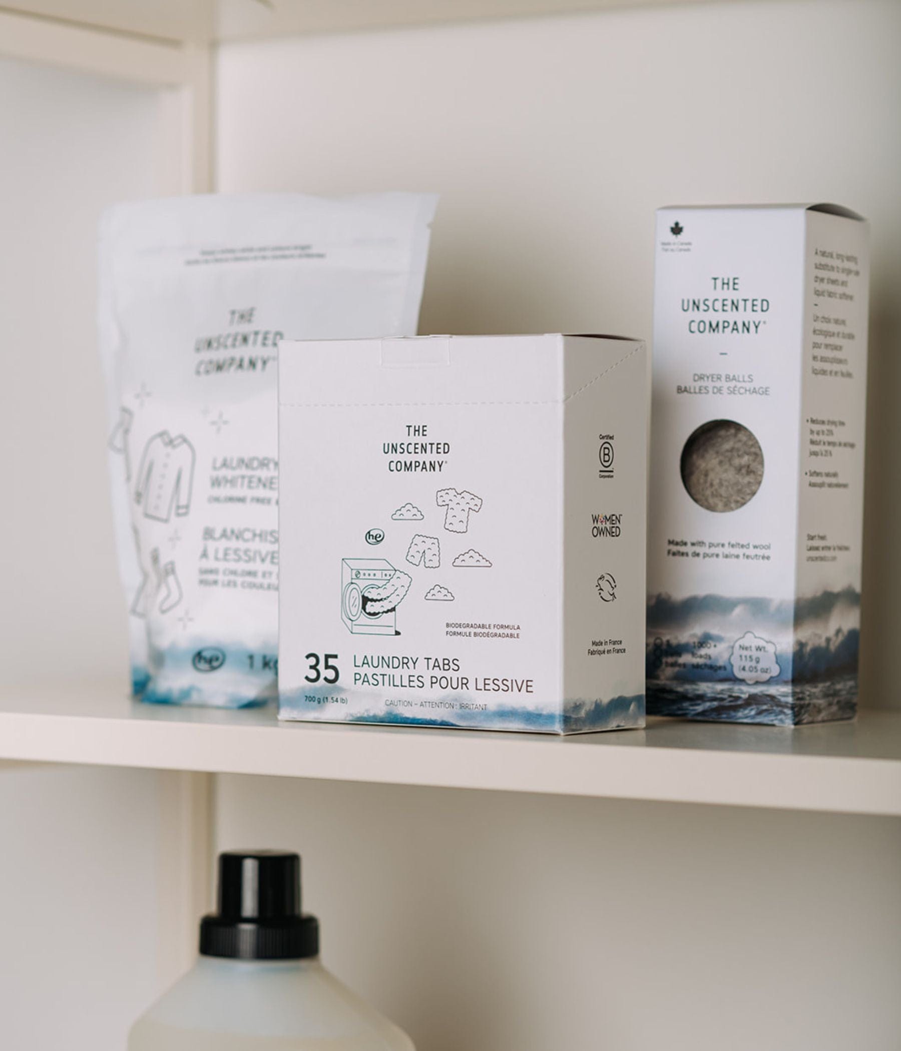 The Unscented Company products on a shelf: Laundry Whitener pouch, 35 Laundry Tabs box, and Dryer Balls box. Part of a laundry detergent bottle is visible below.