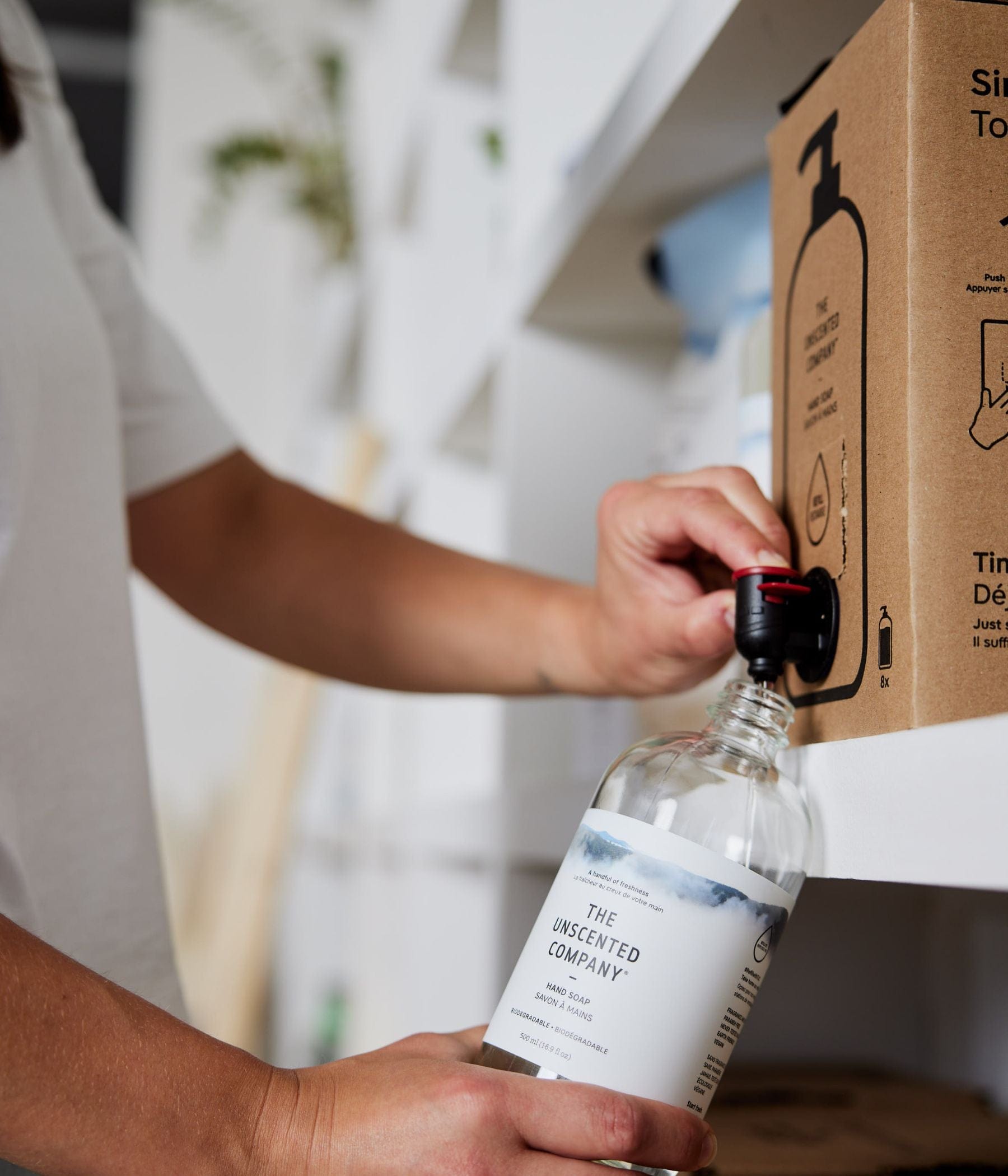Refilling a bottle of The Unscented Company hand soap from a box.