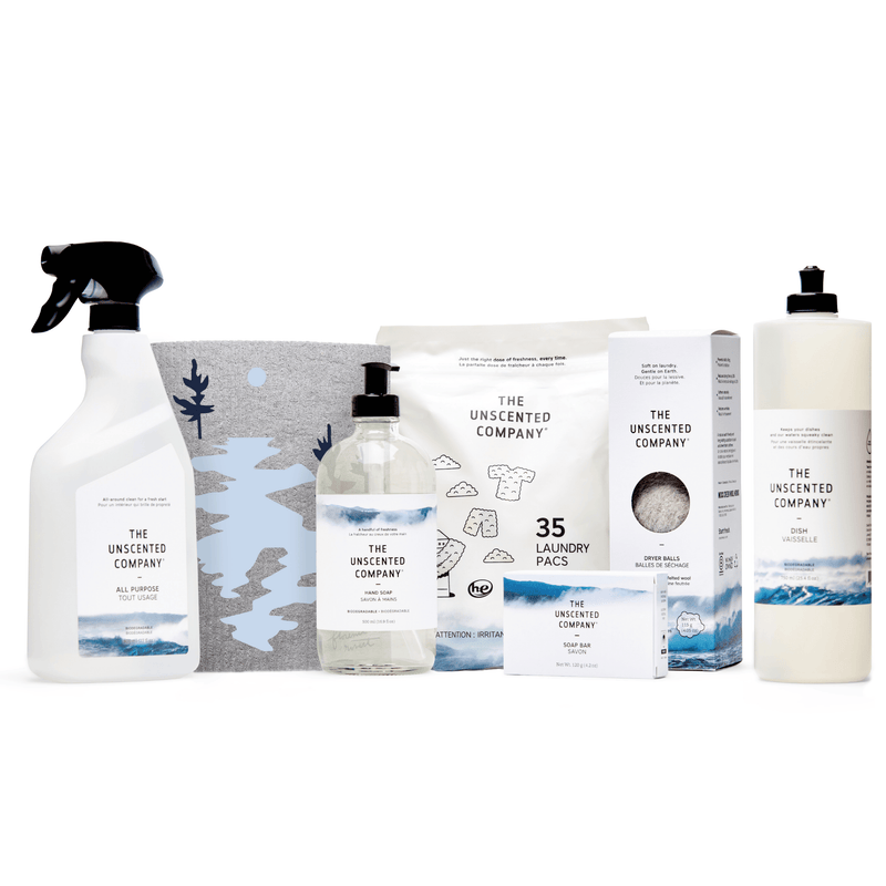 Set of The Unscented Company products including an all-purpose cleaner, illustrated reusable bag, hand soap, laundry pacs, soap bar, dryer balls, and dish soap, neatly arranged on a white background.