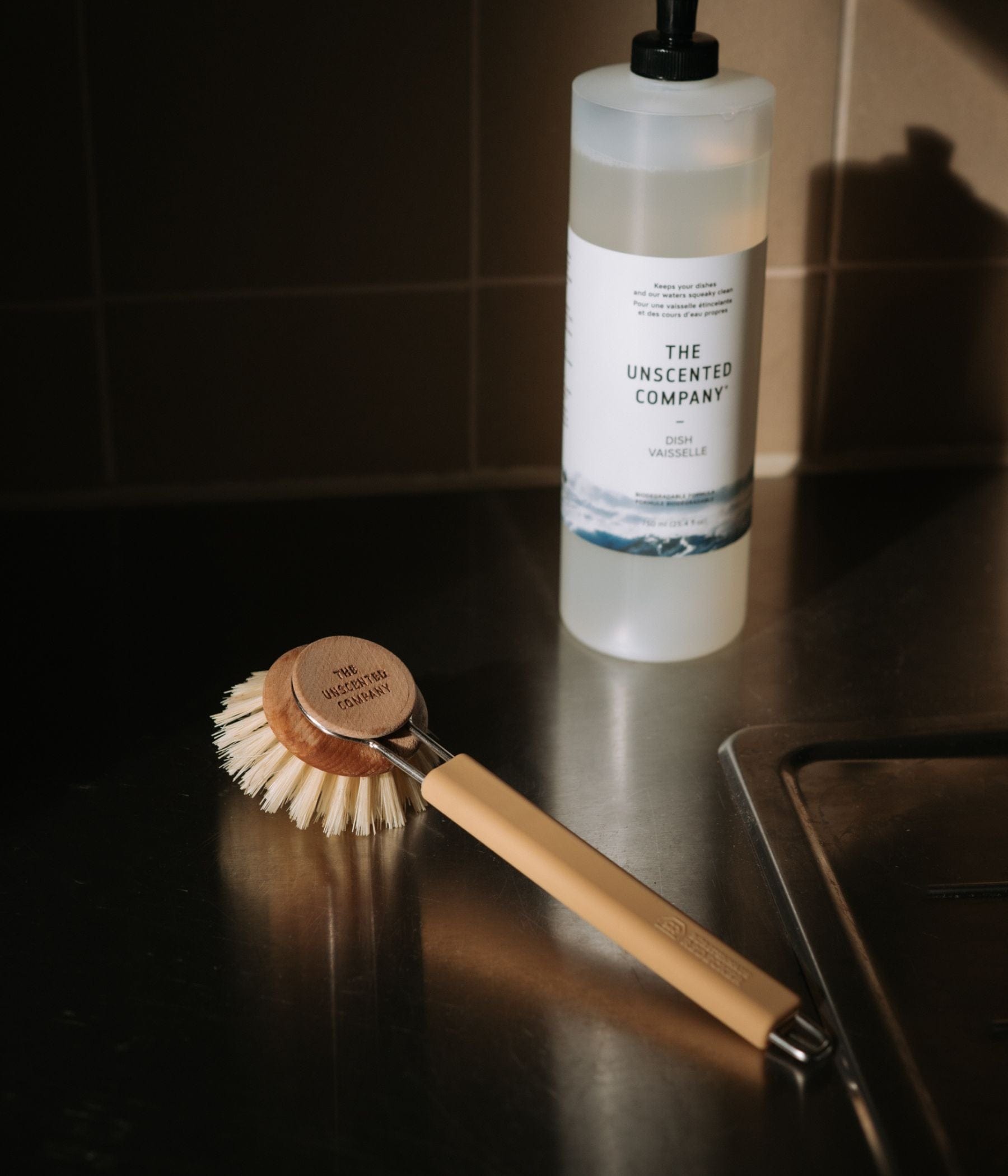 The Silicone Dish Brush Handle + Wood Dish Head in Sand with a 750ml Dish Soap bottle on the right.