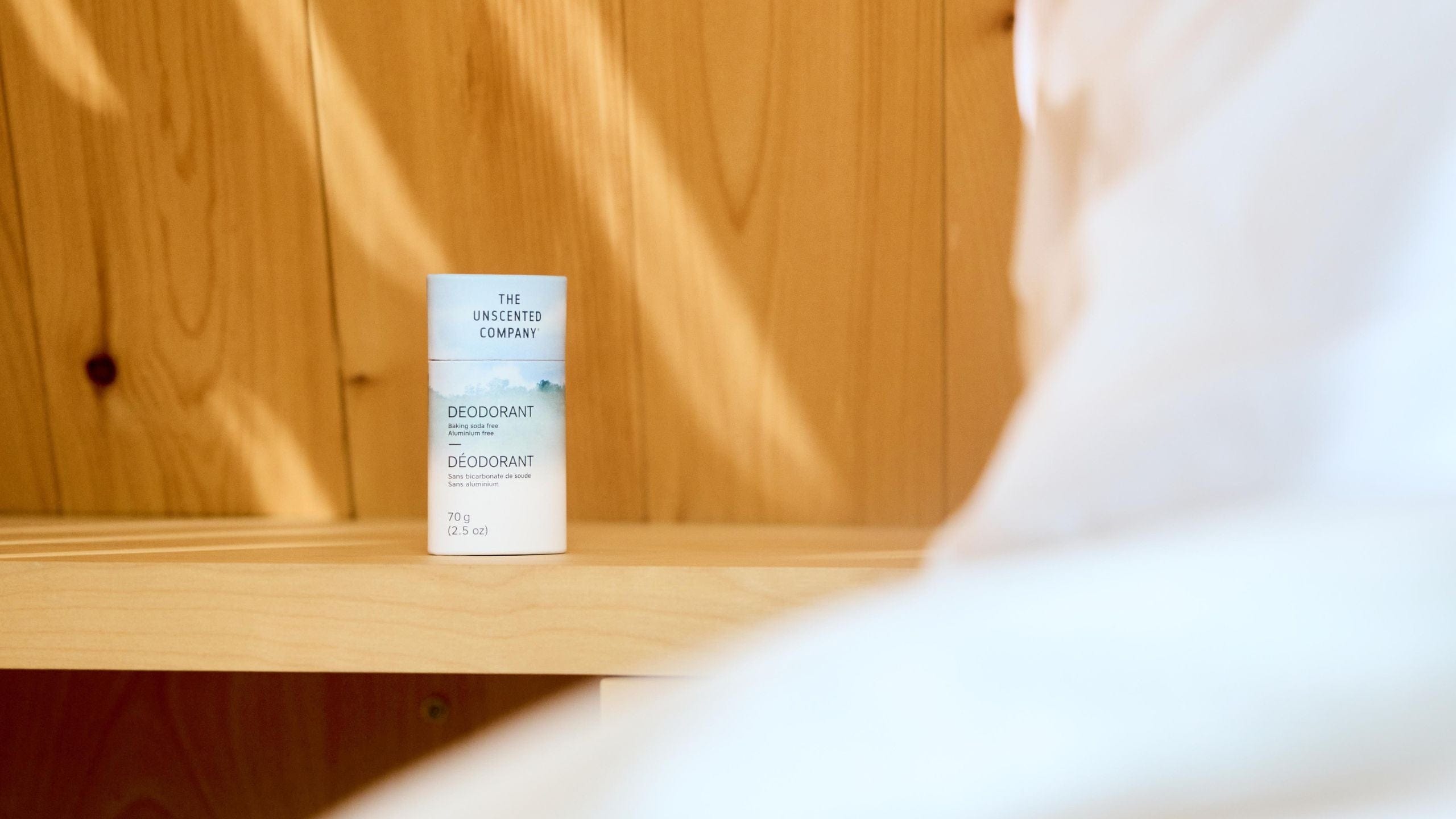 A The Unscented Company deodorant stick on a wooden shelf.