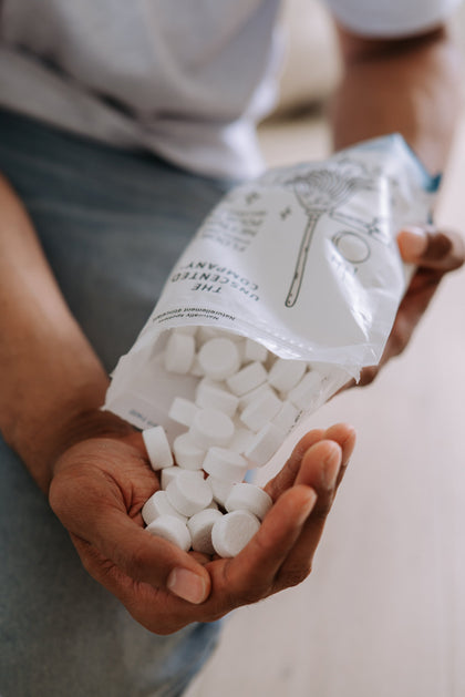 Person holding a package of white tablets with a blurred background