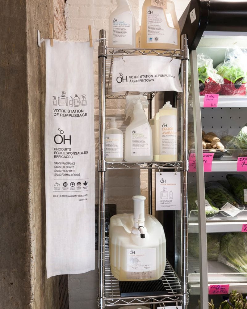 OH refill station with cleaning products next to a fridge with vegetables.