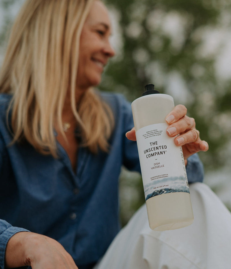 Blonde woman holding a bottle of The Unscented Company Dish Soap