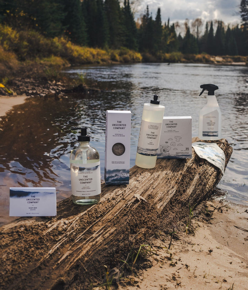 The Unscented Company products displayed on a log by a river.