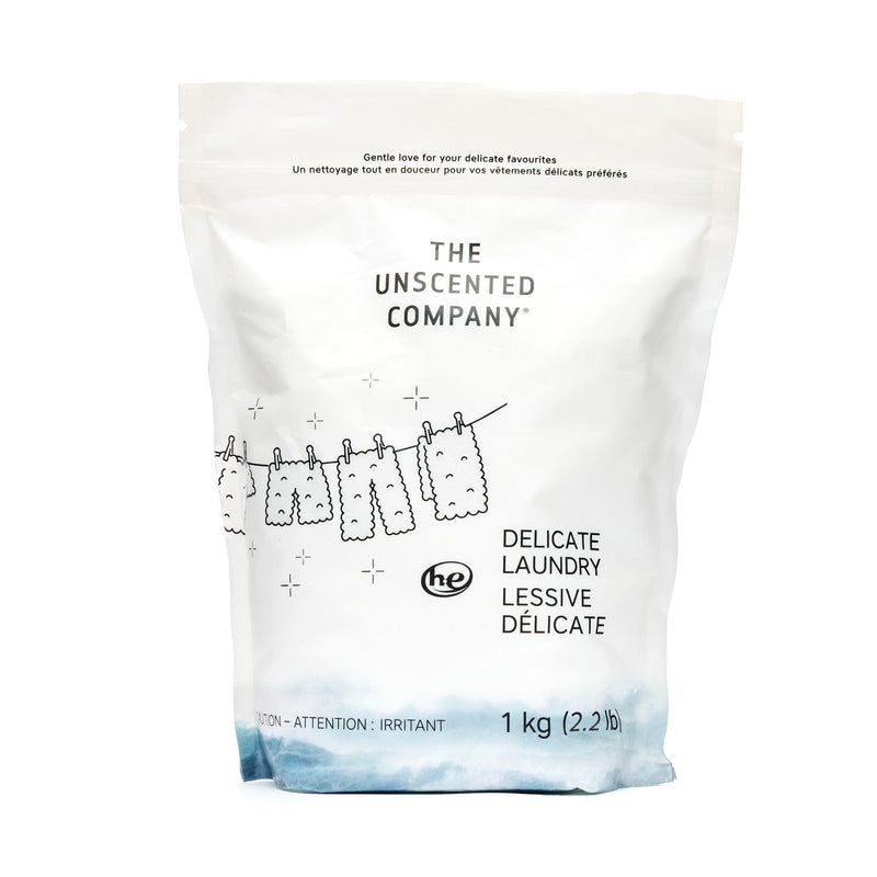 1 kg The Unscented Company delicate laundry detergent bag, featuring a clothesline illustration with garments hanging, set against a white background with a wave design at the bottom.