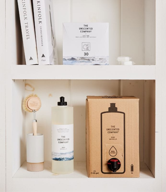 Dishwashing products from The Unscented Company displayed on white shelves.
