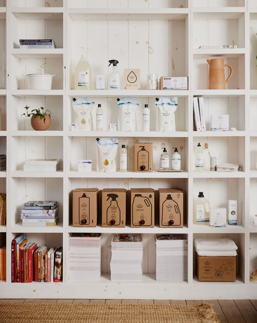 Shelves filled with The Unscented Company products, books, and decor in a bright, cozy room.
