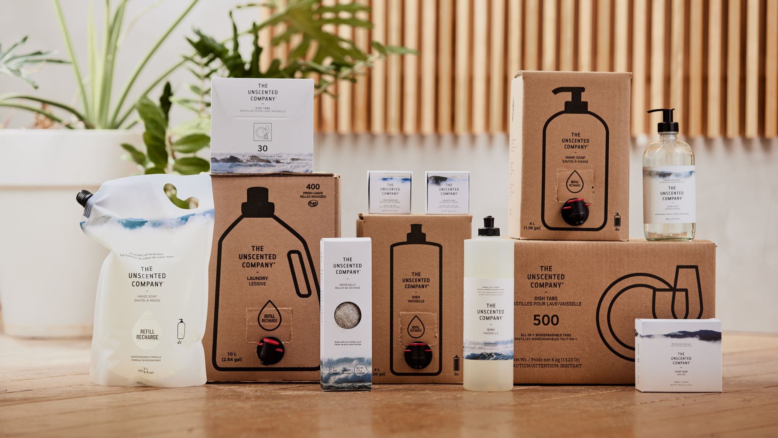 Assortment of The Unscented Company cleaning products, refills, and packaging displayed on a wooden floor.