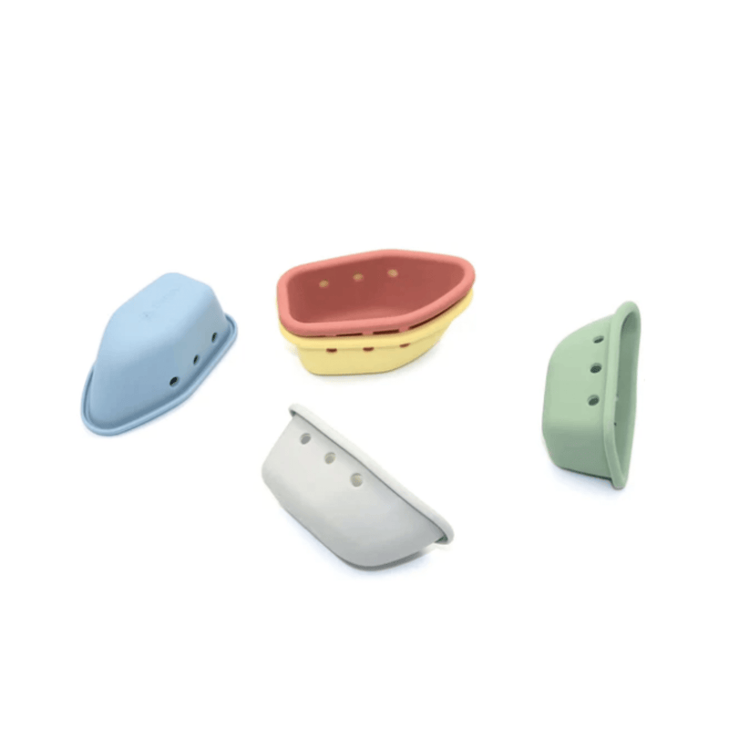 Quatre bateaux jouets en silicone colorés en bleu, rouge, jaune et vert.