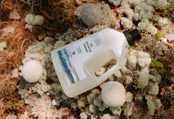 The Unscented Company laundry detergent bottle with wool dryer balls on natural moss