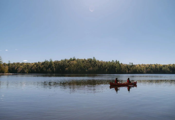 Canoe on a calm lake surrounded by forest during a camping trip