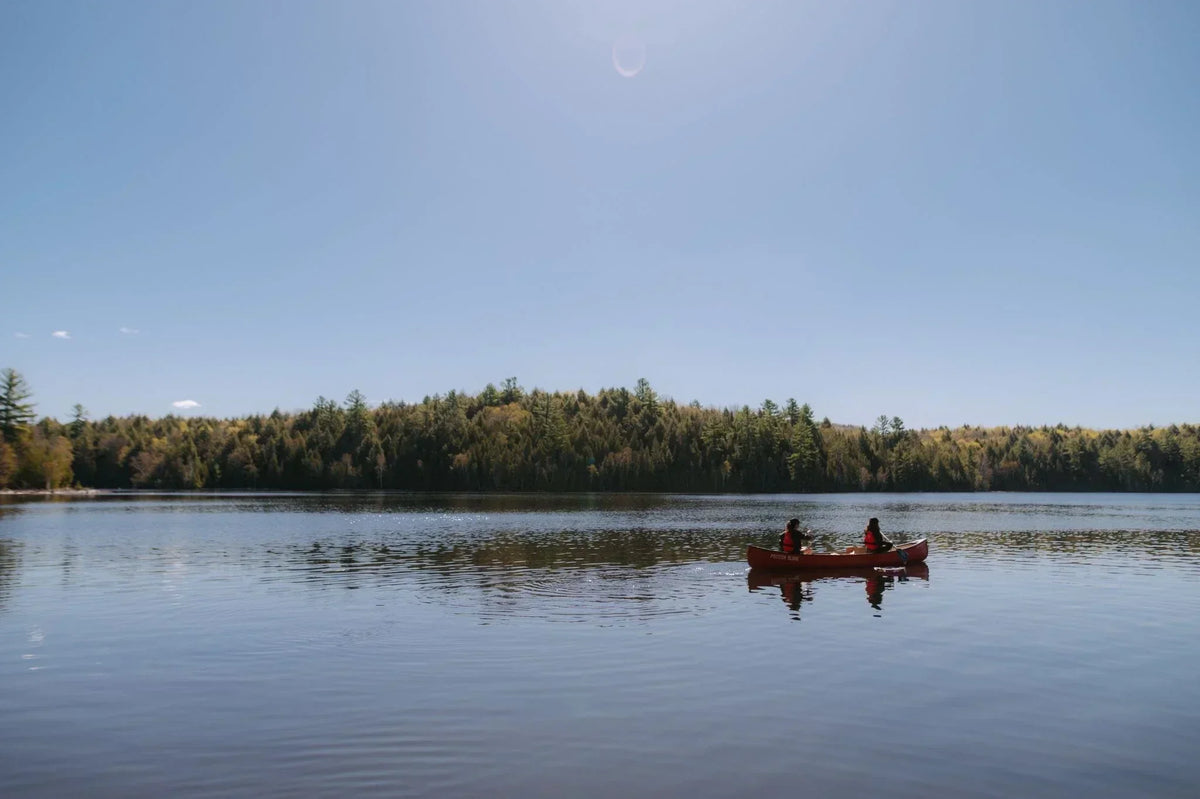 Canoe on a calm lake surrounded by forest during a camping trip