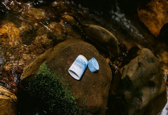 Fragrance free deodorant tube resting on a mossy rock beside a stream