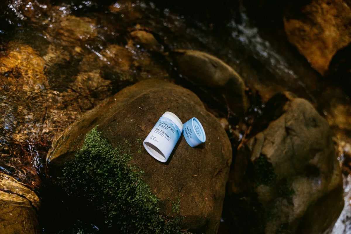 Fragrance free deodorant tube resting on a mossy rock beside a stream