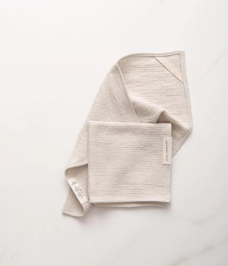  Light beige textured cloth folded on a white surface.