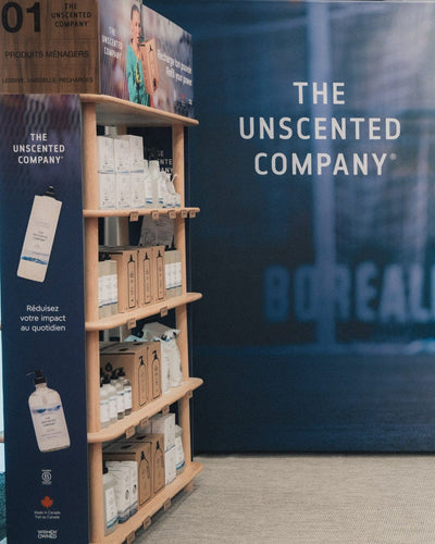 The Unscented Company eco-friendly cleaning products displayed at a retail booth, featuring refillable bottles, bulk refill boxes, and minimalist packaging, promoting Canadian-made sustainable home care solutions and a zero-waste lifestyle.
