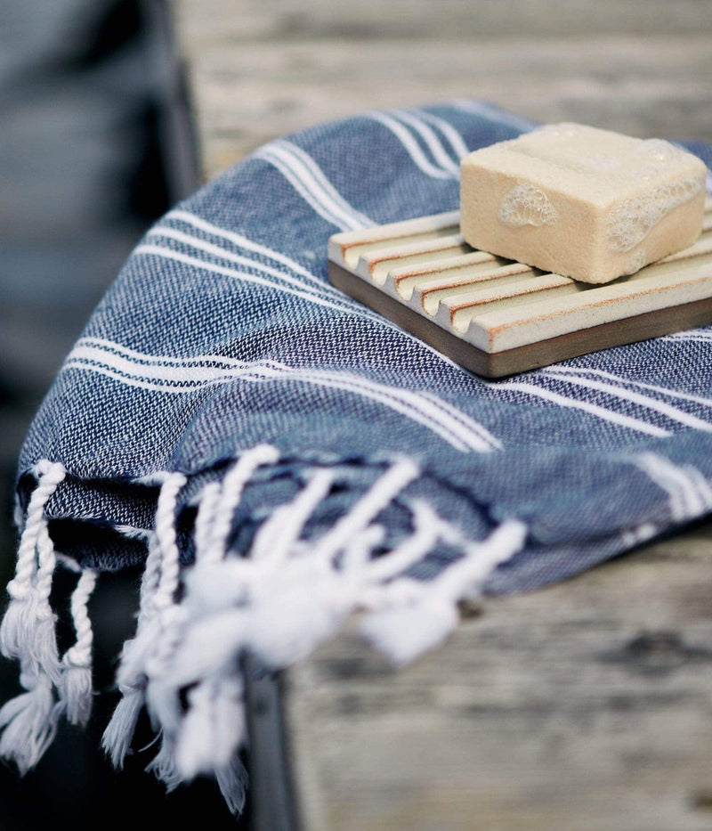 Savon sur un porte-savon en céramique avec une serviette à rayures bleues.
