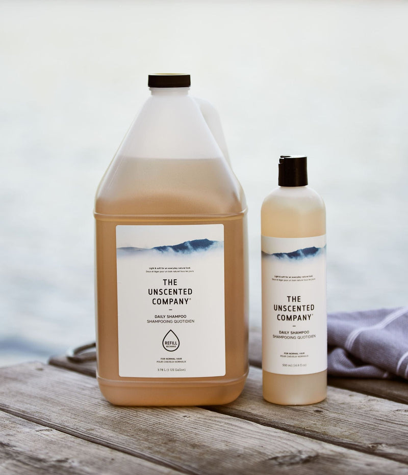 Large refill and regular bottle of shampoo from The Unscented Company on a dock.
