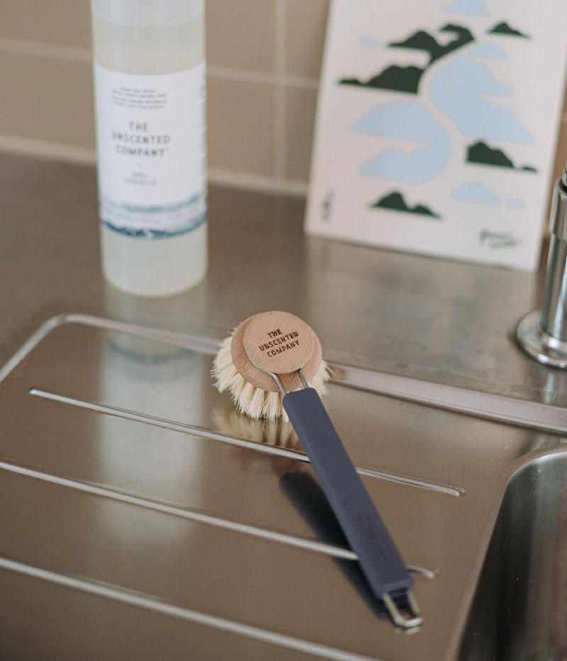 The Silicone Dish Brush Handle + Wood Dish Head in Blue with a 750ml Dish Soap bottle on the top left corner and a KLIIN in the top right corner.