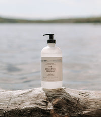 The 500ml Hand Soap in a plastic bottle on a tree branch with a lake in the background.