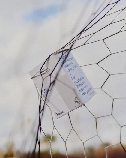 The Unscented Company dish soap box caught in a goal net, floating under a blue sky.