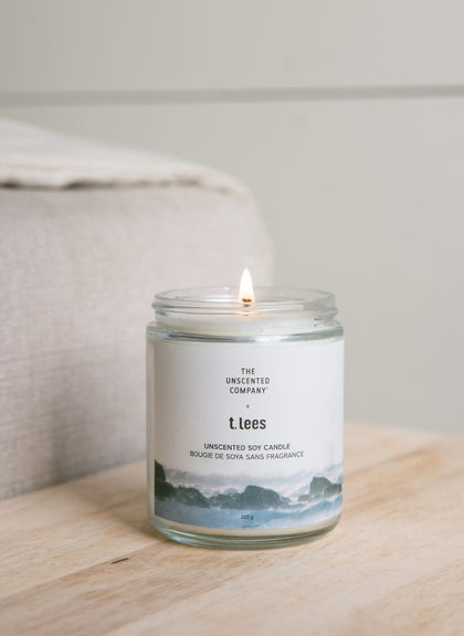 Bougie de soya sans fragrance de The Unscented Company x t.Lees allumée sur une surface en bois.
