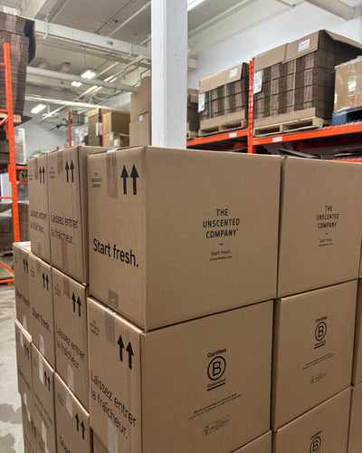 The Unscented Company shipping boxes stacked in a warehouse, showcasing eco-friendly packaging, recyclable materials, and large-scale distribution of sustainable, Canadian-made cleaning products with a low-impact, zero-waste approach.